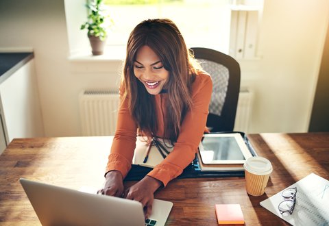 happy woman of colour using a laptop